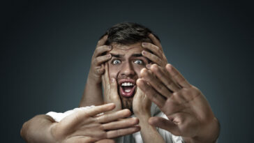 un modello maschile circondato da mani come i suoi pensieri su un muro scuro